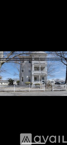 A two-story house with a white picket fence in front.