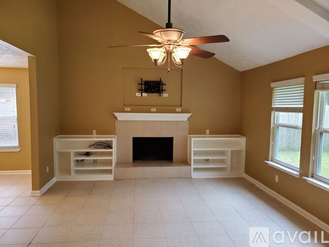 A living room with a fireplace and a ceiling fan.