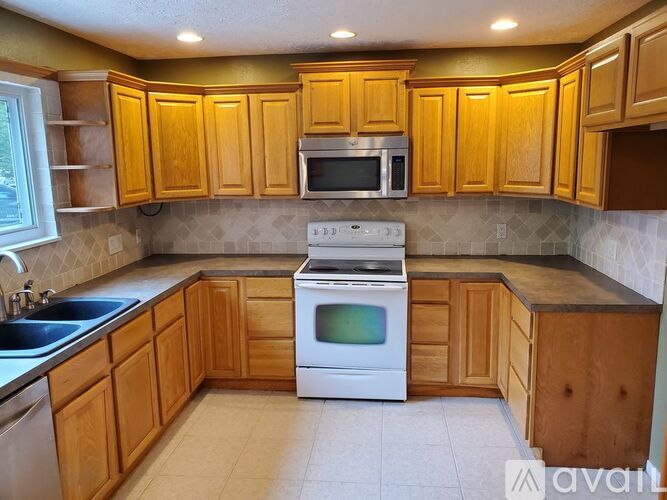 A kitchen with wooden cabinets and a white stove top oven.