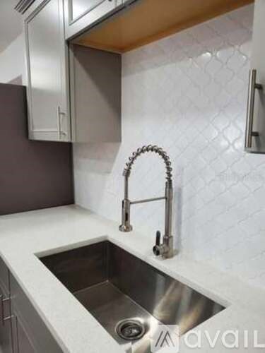A kitchen sink with a chrome faucet and a white countertop.