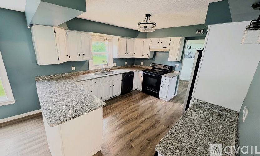 A kitchen with a granite countertop and white cabinets.
