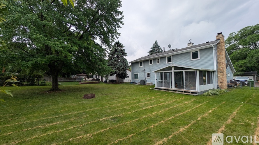 A house with a large lawn and trees in the background.