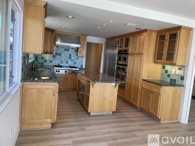 A kitchen with wooden cabinets and a green backsplash.