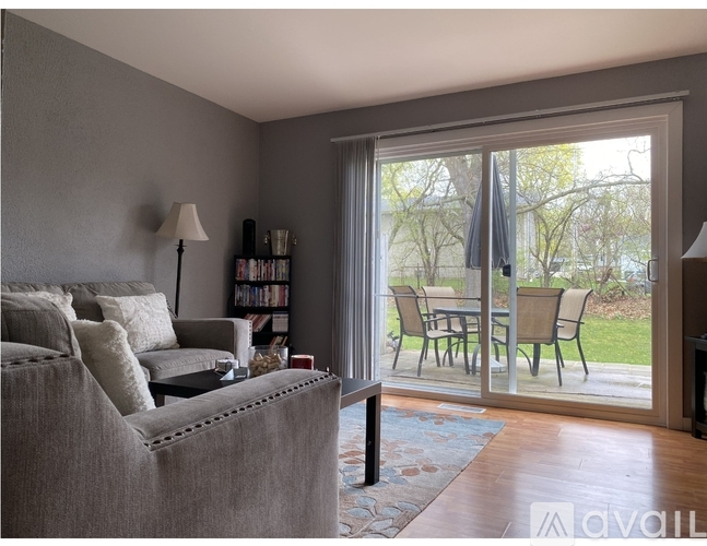 A living room with a grey couch and a glass door leading to a patio.