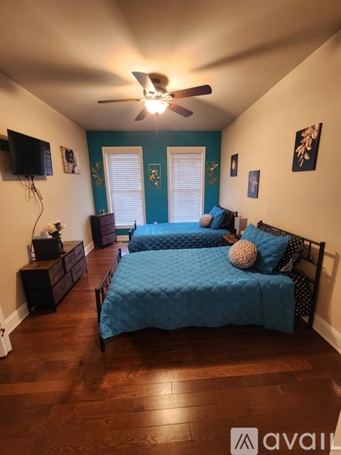 A bedroom with two beds and a ceiling fan.