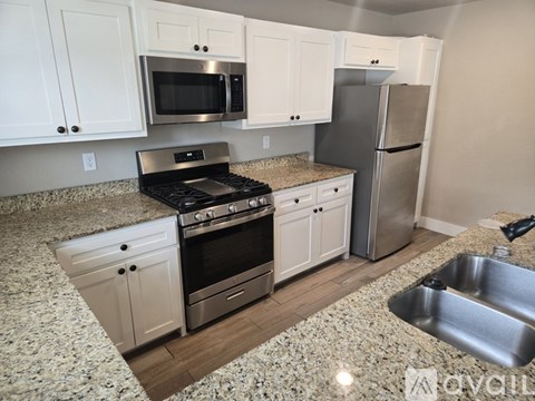 A kitchen with white cabinets and a granite countertop.