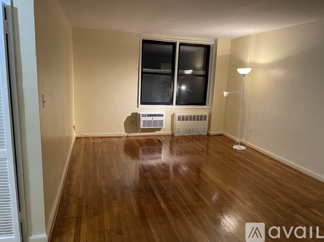 A room with wooden floors and a window with blinds.