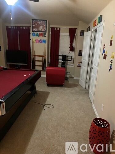 A room with a pool table and a red ottoman.