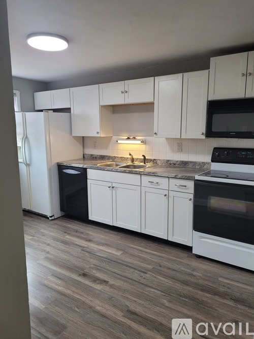 A kitchen with white cabinets and a wooden floor.