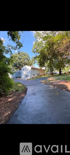 A white building is surrounded by greenery and a paved pathway.