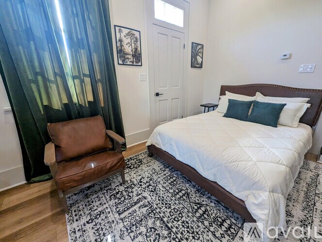 A bedroom with a large bed and a chair.