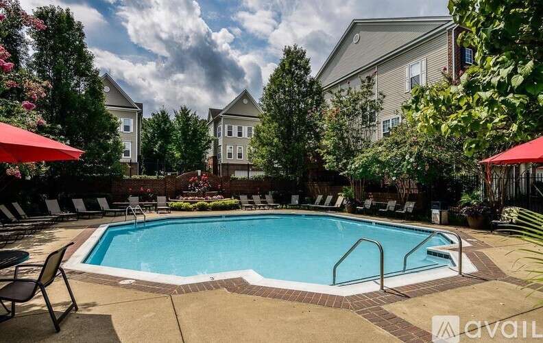 A pool surrounded by lounge chairs and umbrellas with apartment buildings in the background.