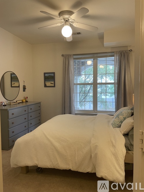 A bedroom with a white bed and a ceiling fan.