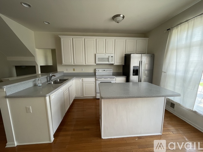 A kitchen with white cabinets and a grey countertop.