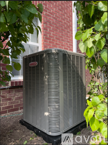 A large outdoor air conditioning unit sits in front of a brick building.