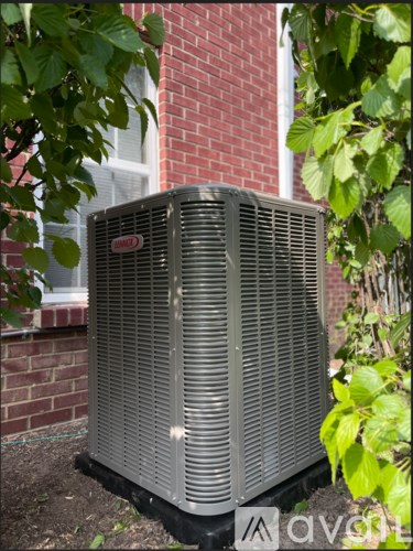 A large outdoor air conditioning unit sits in front of a brick building.
