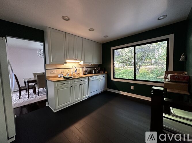 A kitchen with white cabinets and a large window.