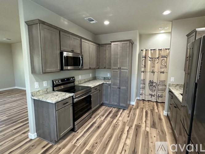 A kitchen with wooden floors and a refrigerator on the right.