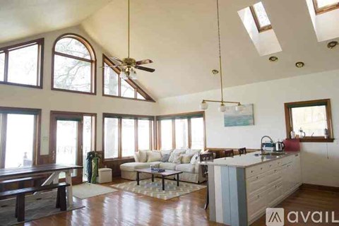 A spacious living room with a kitchen area in the background.