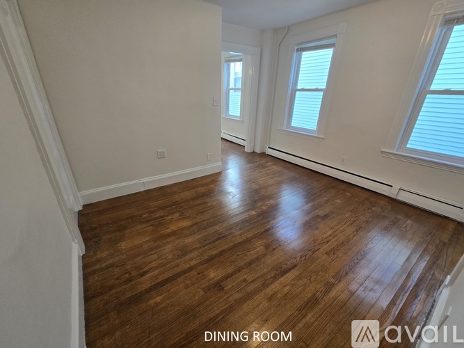 A dining room with wooden floors and white walls.