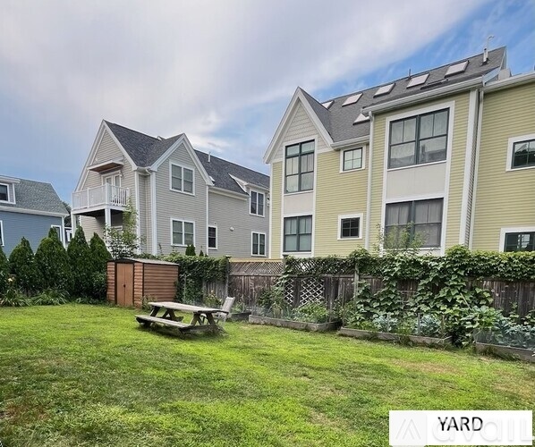 A grassy yard with a picnic table and apartment buildings in the background.