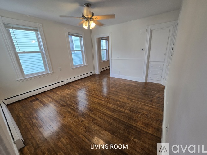 A living room with wood flooring and a ceiling fan.
