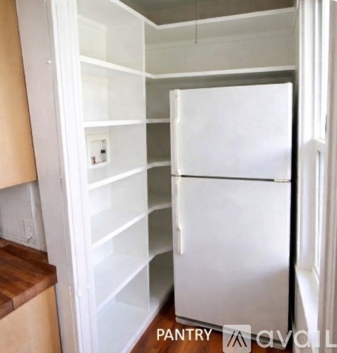 A white refrigerator in a kitchen with a wooden floor.