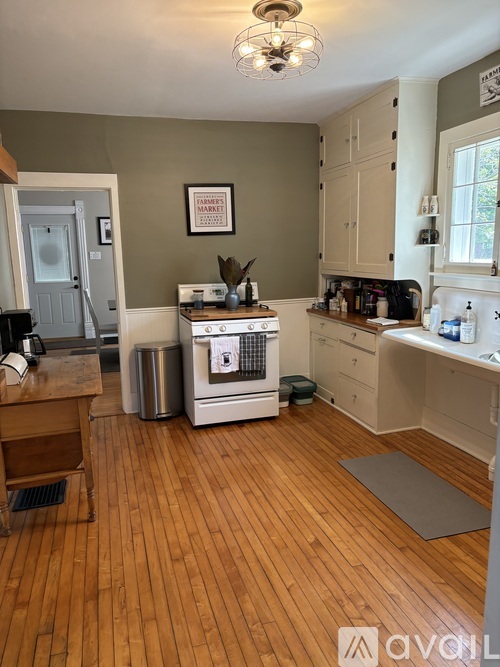 A kitchen with wooden floors and a white stove top oven.