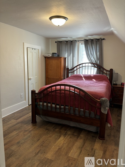 A bedroom with a red bed and wooden floors.
