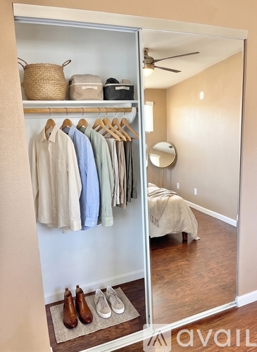 A bedroom with a closet full of clothes and a mirror on the wall.