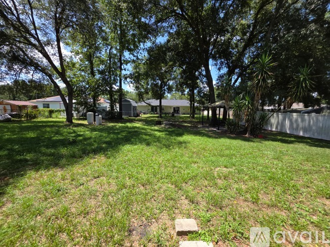 A grassy area with trees and a fence in the background.