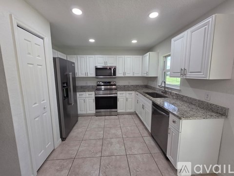 A kitchen with white cabinets and a granite countertop.