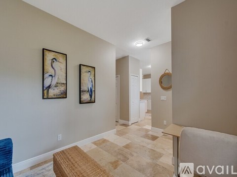 A hallway with two framed pictures of birds on the wall and a blue chair on the left.