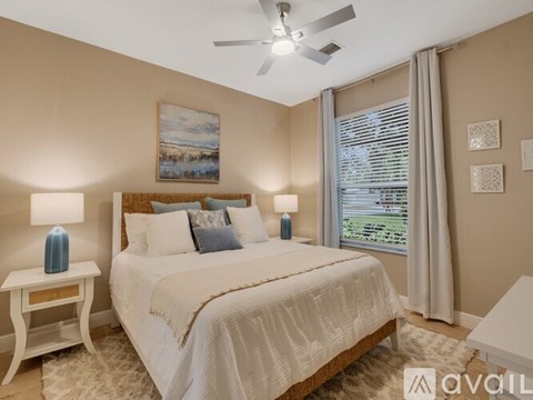 A bedroom with a large bed, a ceiling fan, and a painting on the wall.