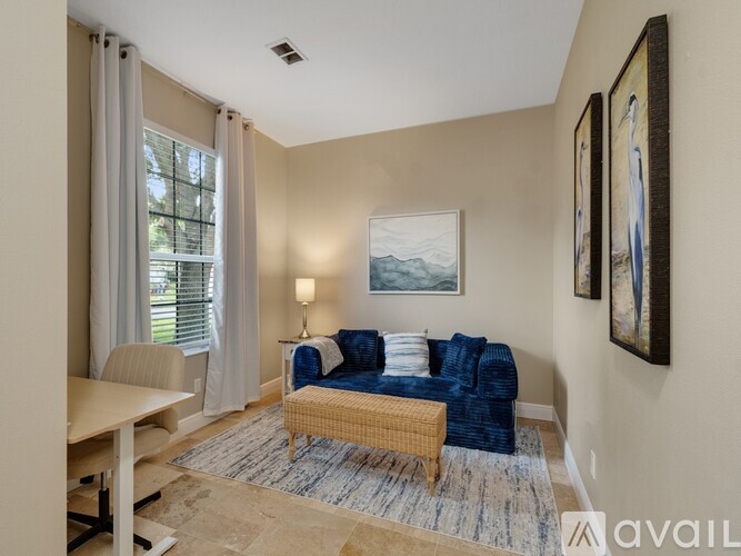 A living room with a blue couch and a painting on the wall.
