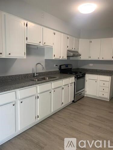 A kitchen with white cabinets and a grey countertop.
