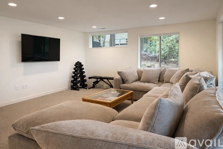 A living room with a large sectional sofa and a flat screen TV mounted on the wall.
