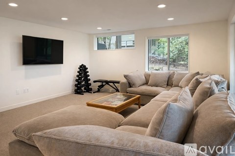 A living room with a large sectional sofa and a flat screen TV mounted on the wall.