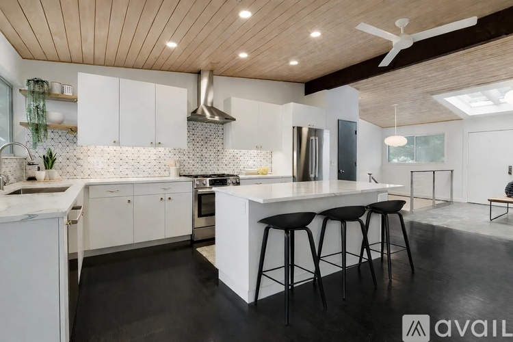 A modern kitchen with white cabinets and black stools.