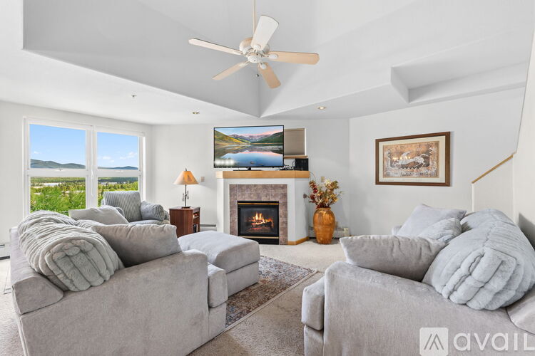 A living room with a grey couch, a fireplace, and a painting on the wall.