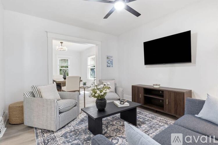 A living room with a striped chair, a black coffee table, and a flat screen TV mounted on the wall.