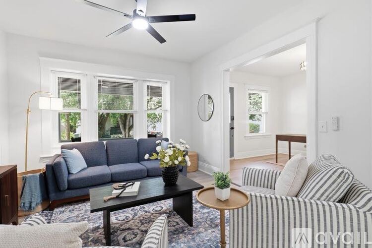 A living room with a grey sofa, a striped armchair, a coffee table, and a ceiling fan.