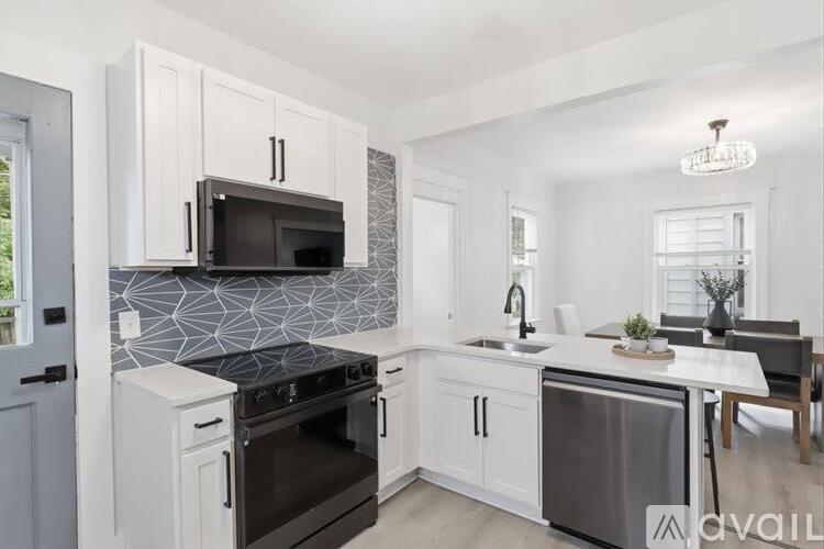 A modern kitchen with white cabinets and a black microwave.
