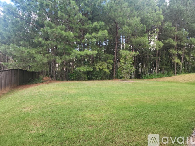 A grassy field with trees in the background and a fence on the left side.