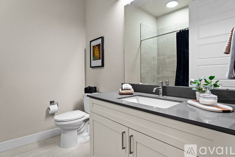 A bathroom with a toilet, sink, and mirror.