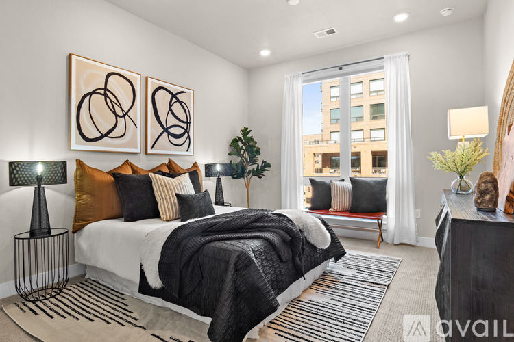 A bedroom with a large bed, a nightstand with a lamp, and two framed artworks on the wall.