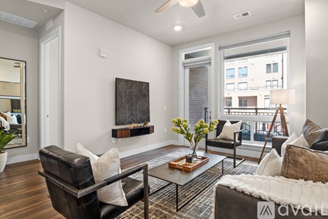 A living room with a black leather couch, a coffee table, and a painting on the wall.