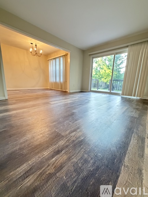 A spacious room with wooden flooring and a chandelier.
