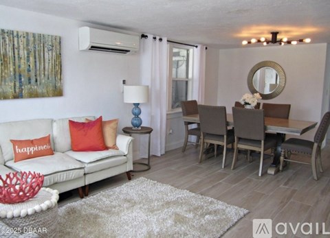 A living room with a white couch, a round mirror, and a painting on the wall.