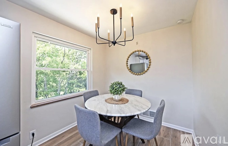A dining room with a round table and grey chairs.